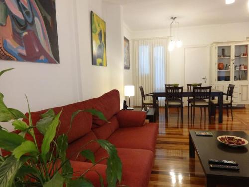 uma sala de estar com um sofá vermelho e uma mesa em Apartamento Puente Colgante em Getxo