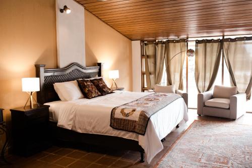 a bedroom with a large bed and a chair at Hotel Los Olivos Santiago Atitlan in Santiago Atitlán