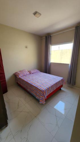 - un lit dans une chambre avec fenêtre dans l'établissement Casa do Jerff, à Viçosa do Ceará