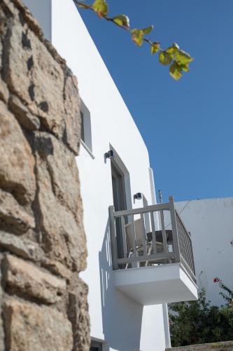 a balcony on a building next to a stone wall at Fabrikas in Mýkonos City