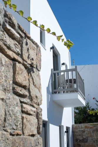 a white building with a balcony next to a stone wall at Fabrikas in Mýkonos City