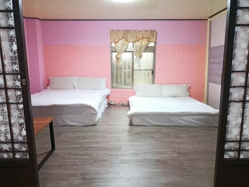 a pink room with two beds and a window at Bokelai B&B in Renai