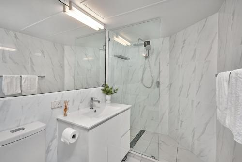 a white bathroom with a sink and a shower at Golden Sands Beachfront Resort in Yorkeys Knob