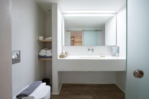 a white bathroom with a sink and a mirror at Fabrikas in Mýkonos City