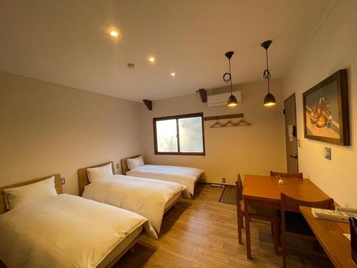 a room with two beds and a table and a desk at cafe&stay CASTANA in Matsumoto