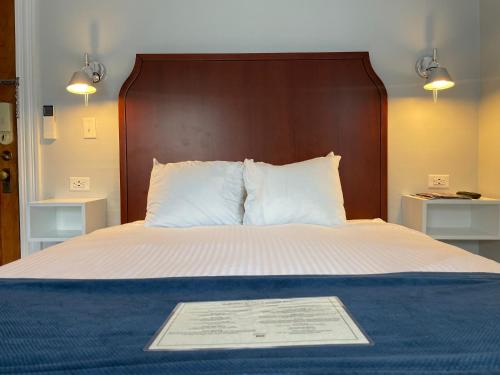 1 cama con cabecero de madera y placa en Emerson Inn By The Sea, en Rockport