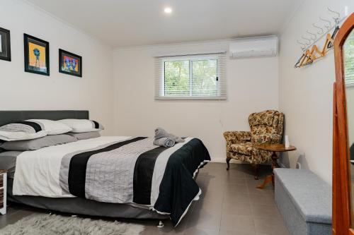 a bedroom with a bed and a chair and a window at Stay in Blackwood in Blackwood