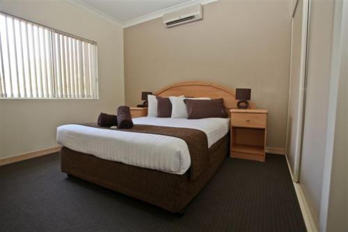 a hotel room with a large bed and a night stand at Alice On Todd Apartments in Alice Springs