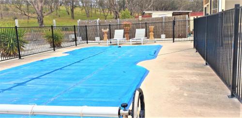 a swimming pool next to a fence with two chairs at Alma Retreat, King bed, Family, Pet Friendly in Alma