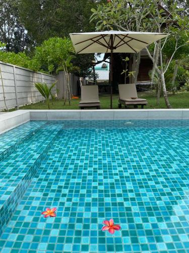 a swimming pool with two flowers in the water at The Temak Villa in Pantai Cenang