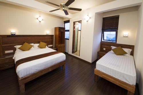 a bedroom with two beds and a ceiling fan at Tropic Tree Maldives in Gulhi