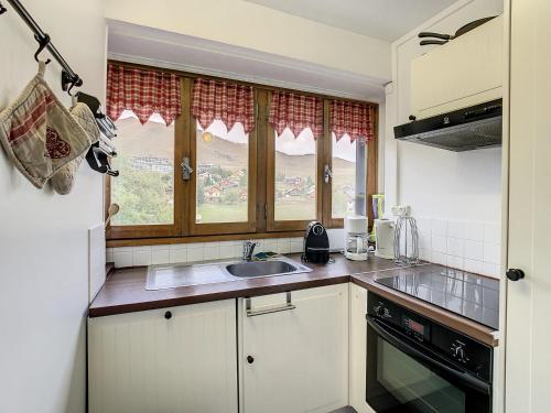 une cuisine avec des armoires blanches, un évier et une fenêtre dans l'établissement Appartement lumineux 6 pers, style montagne, balcon sud, proche commerces et pistes - FR-1-417-151, à La Toussuire