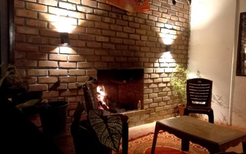 a brick fireplace with a fire in it at Coorg Coffee Park Farmstay in Somvārpet