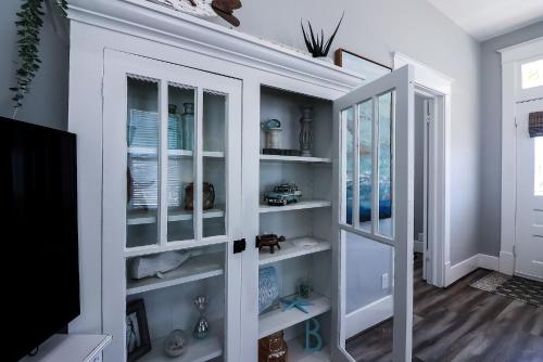 Habitación con estanterías blancas y TV en The Old Flamingo Vibrant Bungalow just 2 mins from the beach, en Galveston