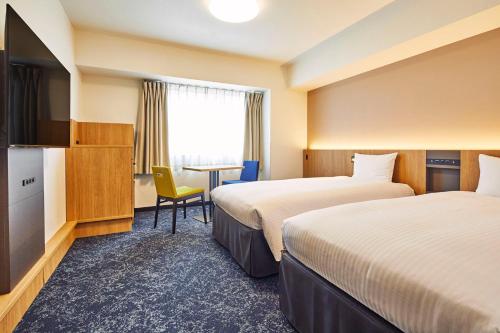 um quarto de hotel com duas camas e uma televisão em Hotel Lumiere Kasai em Tóquio