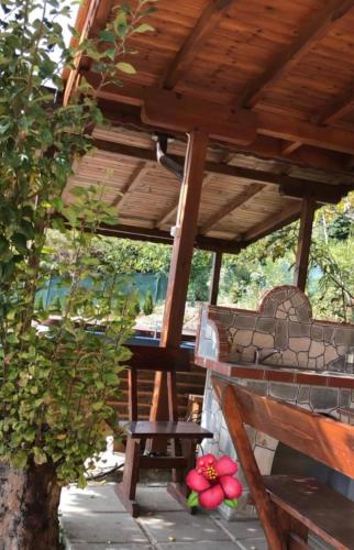 a wooden porch with a bench under a wooden roof at Sunshine villa Dzhigurovo in Sandanski