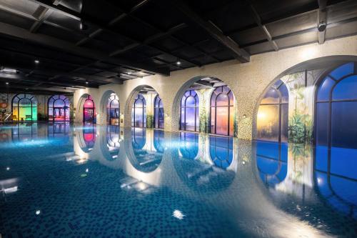 a swimming pool in a building with paintings on the walls at Venus Hotel Tam Đảo in Tam Ðảo