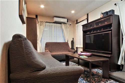 uma sala de estar com um sofá e uma televisão em Homestay Intimo Amigo em Tóquio