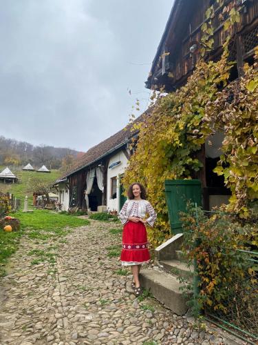 a girl in a red dress standing next to a building at Saschiz 130/Lodging and Glamping in Saschiz