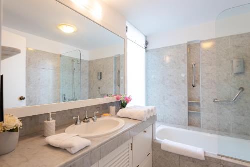 a bathroom with a sink and a tub and a mirror at OceanFront Larcomar Apartments in Lima