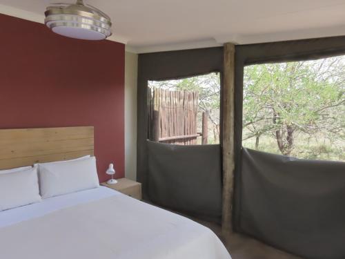 a bedroom with a bed and a large window at Sunset Lodge & Safaris in Guernsey Nature Reserve
