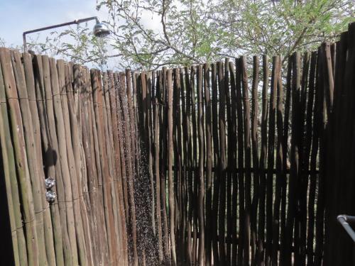 a wooden fence with a tree behind it at Sunset Lodge & Safaris in Guernsey Nature Reserve
