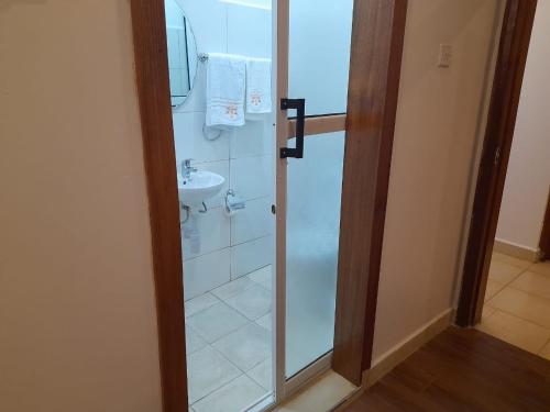 W łazience znajduje się prysznic i umywalka. w obiekcie Hellenis Guest House w mieście Kakamega