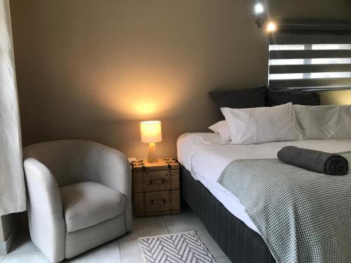 a bedroom with a bed and a chair and a lamp at Aluve Guesthouse in Johannesburg