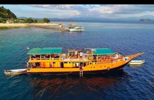 a yellow boat in the water with people on it at Liveaboard komodo Tour 2Days 1Night share trip in Labuan Bajo