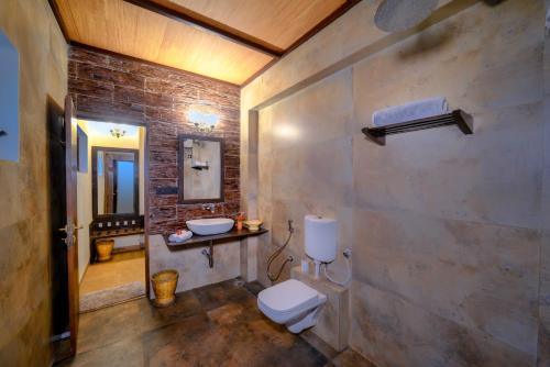 a bathroom with a white toilet and a sink at Aranyak Resort Kanha in Dhanwār