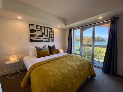 a bedroom with a large bed and a large window at Lakefront Gem, Absolute Waterfront in Queenstown