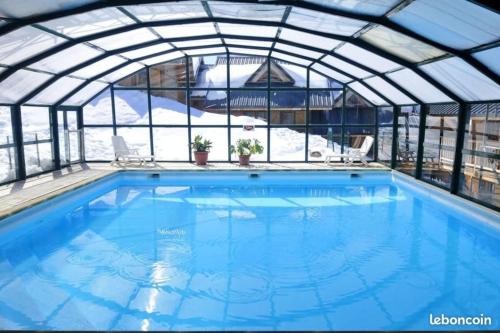 an indoor swimming pool with a glass roof at Location à la Montagne avec piscine été / hiver vg23 in Saint-François-Longchamp