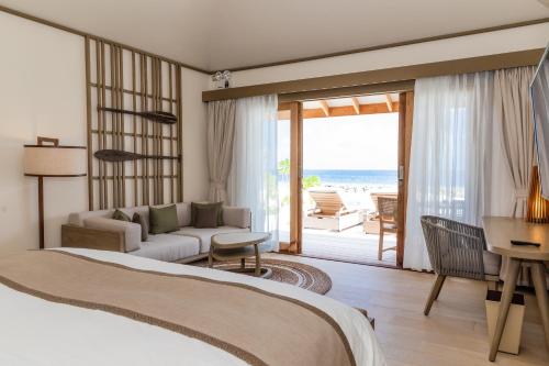 a bedroom with a bed and a living room at Kagi Maldives Resort & Spa in North Male Atoll