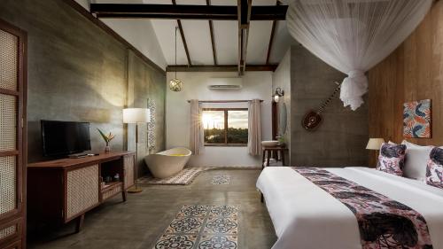 a bedroom with a bed and a tub and a television at Dontrei Villa Angkor in Siem Reap