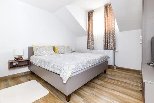 a white bedroom with a bed and a window at Harmonija Lux in Vrdnik