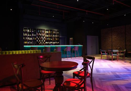 a room with tables and chairs and a bar with wine bottles at Basqal Resort & SPA in Basqal