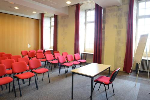 a conference room with red chairs and a table at Hôtellerie Saint Yves in Chartres