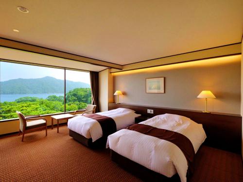 a hotel room with two beds and a large window at Jodogahama Park Hotel in Miyako