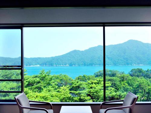 a room with a large window with a view of a lake at Jodogahama Park Hotel in Miyako