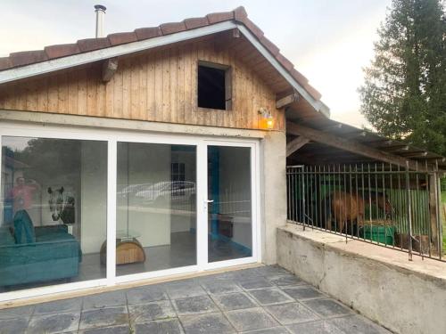une maison avec une grande porte coulissante en verre dans l'établissement LE PETIT RANCH DU CLOS DE LA CHEVAUCHÉE, à Thurey-le-Mont