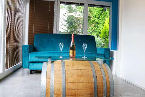 a bottle of wine and two wine glasses on a barrel at LE PETIT RANCH DU CLOS DE LA CHEVAUCHÉE 