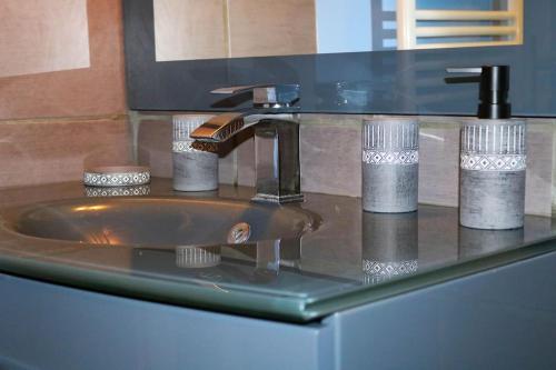 a bathroom sink with a glass counter with a faucet at LE PETIT RANCH DU CLOS DE LA CHEVAUCHÉE 