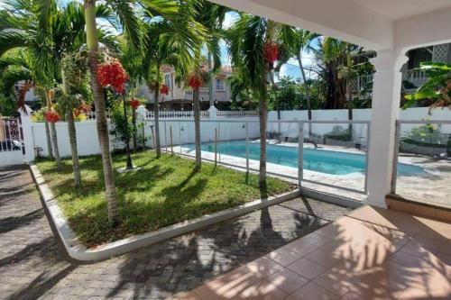 ein Haus mit einem Pool und Palmen in der Unterkunft Villa Palmira 6 suites avec piscine 5 min à pied de la plage Pereybere in Pereybere