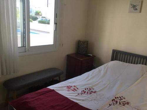 een slaapkamer met een bed en een raam en een raam bij Appartement Limnos Gardens in Paphos City