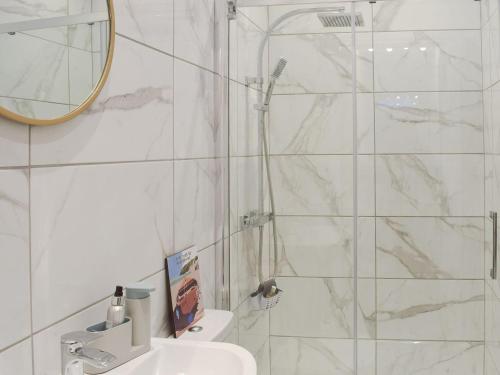 a bathroom with a shower and a sink and a mirror at Hunter Links Cottage in Prestwick