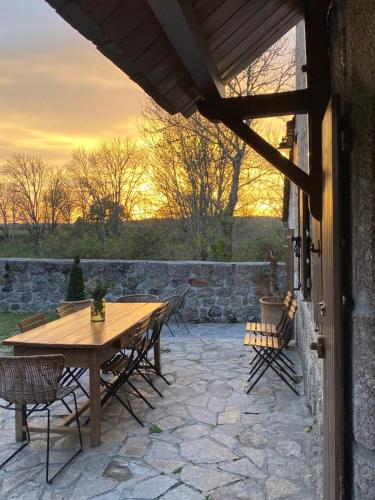 einen Holztisch und Stühle auf einer Steinterrasse in der Unterkunft La Maison de Paul en Aubrac - Lozère in Fontans