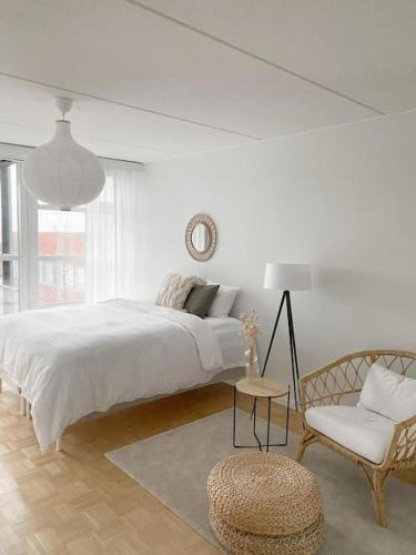 a white bedroom with a large bed and a chair at Modern and cozy apartment with Sauna in Espoo