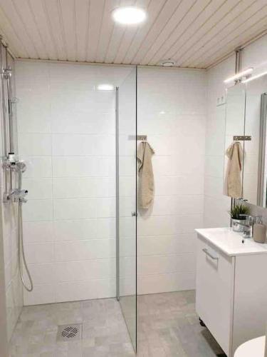 a bathroom with a glass shower and a sink at Modern and cozy apartment with Sauna in Espoo