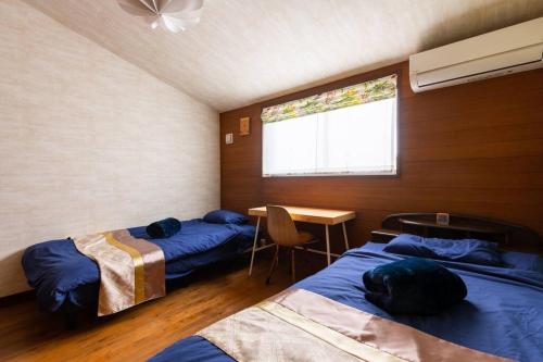 a room with two beds and a table and a window at オーシャニア一宮 in Ichinomiya