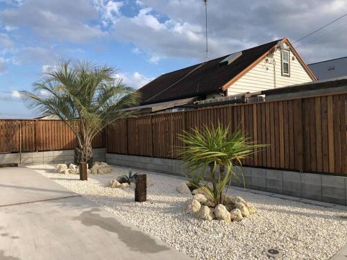 a house with a fence and two palm trees at オーシャニア一宮 in Ichinomiya